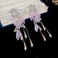 Detail of tassel earrings with pink petals, crystal bow, and silver chains on black velvet - Pink