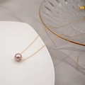 Collana minimalista in oro con pendente di perla lavanda su un piatto di ceramica bianca - Perla Edison da 10MM