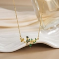 Close-up of bird pendant with blue enamel and green gemstone leaves on a gold chain - FN0124 Bird on Branch Enamel Multi-color