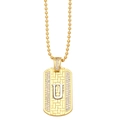 Macro detail of a gold military dog tag pendant with sparkling pavé letter U and bead chain - Letter U