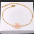 Detalle de pulsera de acero inoxidable dorado con colgante de flor de circón rosa - Flor Rosa