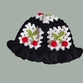 Detail of handmade knit bucket hat featuring white wavy brim and red cherry decorations - One Size / Cherry White