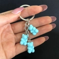 Handheld view of three creative blue resin cartoon bear keychains with metal chains - Blue