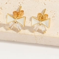 Macro view of gold bow earrings with white enamel and sparkling rectangular zircons - White Bowknot (ES2644)