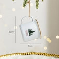 White enamel mug Christmas ornament with pine tree design and BELIEVE text hanging - Christmas Tree Mug Ornament