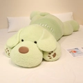 Lying light green plush dog pillow wearing a Happy sweater on a white cozy bed - Matcha Green