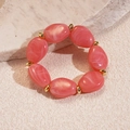 Close-up of pink acrylic oval beads and golden metal spheres on elastic bracelet - Pink