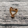 Vista macro di un anello a cuore fluido con finitura dorata lucida su tessuto strutturato - US 7 / Oro