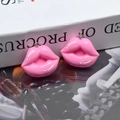 Vista macro detallada de dos dijes de labios de resina rosa brillante con ganchos de metal para DIY - Labios Rosados