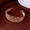 Detalle de pulsera abierta multicapa dorada con cuentas sobre elegante satén - Dorado