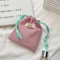 Détail de la pochette en coton à carreaux rouges avec cordon vert et écusson - Carreaux Rouges
