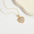 Elegante collar con colgante de corazón dorado y circonitas blancas sobre fondo blanco - Dorado