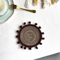 Set de table rond tressé marron et beige avec petits pompons sur surface blanche - 13cm Dessous de verre / café