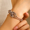 Bracelet tête de mort punk rétro en argent antique porté au poignet d'un modèle - Style Double Squelette (10813)