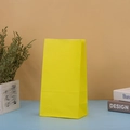 Detailed view of a plain yellow kraft paper gift bag in a minimalist lifestyle setting - Yellow