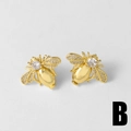Elegantes pendientes de abeja dorados con circonitas brillantes sobre fondo gris claro - Estilo B