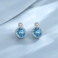 Elegant round blue gemstone stud earrings with silver metal on wavy blue fabric - Stud Earrings / Blue