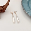 Dettaglio macro di orecchini vintage a goccia con perle barocche e placcatura oro - Orecchini a Clip Lunghi con Cuscinetto Triangolare