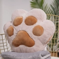 Beige plush cat paw 2-in-1 cushion and blanket combo on a chair in a home setting - Tan