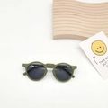 Detail of round dark green kids sunglasses on a wooden display with decorative card - Green