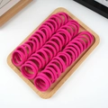 Coleteros elásticos rosas organizados en una bandeja de madera sobre un fondo blanco limpio - 50 Piezas / Rosa oscuro