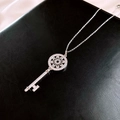 Elegante collana con chiave d'argento e ciondolo a fiore in zircone su pelle nera - Collana a Chiave d'Argento con Fiore Traforato in Zirconia