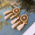 Détail de boucles d'oreilles bohèmes dorées avec pompons blancs et relief floral précis - 14# Crochet Or Blanc