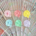 Close-up of translucent Q-shaped resin charms in pastel colors on an iridescent plate - Letter Q