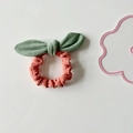 Detailed view of pink fabric scrunchie with green bow knot and soft suede texture - Green Bow