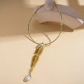 Dettaglio del ciondolo a lisca di pesce dorata con perla barocca su girocollo rigido - Choker Dorato