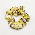 Detailed macro view of a yellow satin hair scrunchie with a vivid baseball print pattern - Yellow Base Football