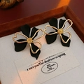 Close-up of black and gold double-layered flower earrings in a premium jewelry box - Silver Earring Post-Black
