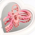 Detailed view of a pink gradient butterfly hair claw on a decorative heart-shaped mirror tray - Deep Pink