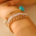 Detail of layered gold chunky chain and turquoise pearl bracelets set on model wrist - Gold-Round