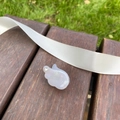 Détail d'une pince à cheveux aile en acétate nacré posée sur un banc avec ruban blanc - Blanc Sirène