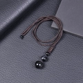 Macro shot of 16mm black obsidian beads on a dark brown braided rope necklace - Obsidian Necklace