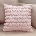 Close-up of pink plush pillow cover with embossed heart pattern on sofa - Pink