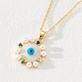 Close-up of golden evil eye pendant with pearls and colorful zircons on textured background - Style F-Pearl Rim Eye