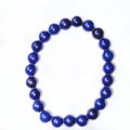 Deep blue lapis lazuli 8mm round bead bracelet with natural gold flecks on white background - Synthetic Lapis