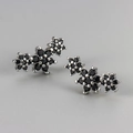 Vista macro de pendientes de flores con circonitas negras engastadas en plata - Color Platino / Strass Negro