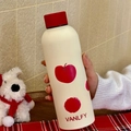 Detail of a matte cream-white thermos with apple pattern and red lid held in hand - 500ml / Red Apple