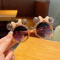 Close-up of cute children's sunglasses with orange glitter frames and round cartoon ears - Yellow
