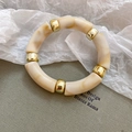 Nahaufnahme des geometrischen Acryl-Armbands in Marmoroptik mit goldenen Trennern - Cremeweiß Marmor (Armband-Beige)