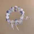 Detail of beaded bracelet with blue stones, crystal beads and a butterfly charm on mirror - Silver-Purple-White / 【product Attributes】a Beaded Bracelet. The Main Material Appears To Be A Blue-purple Natural Cracked Stone (like Agate) Interspersed With Transparent Faceted Crystal Beads. The Embellishments Include A Metal Butterfly Pendant (with A Surface Resembling Crushed Diamonds) And A Delicate Metal Tassel Chain With A Teardrop Pendant.