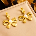 Macro detail of gold-plated bow earrings with pearls on a premium jewelry cushion - E6109
