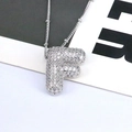 Macro shot of a letter F pendant necklace with pavé cubic zirconia on a silver chain - Letter F