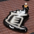 Deep brown ceramic backflow incense burner in Dao character shape on a bamboo mat - Tao