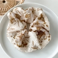 Close-up of beige floral scrunchie with brown leaf pattern on a white plate - Large Leaf Coffee