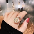 Elegant gold open ring with white pearls and small diamond flower design on a hand model - Pearl Flower