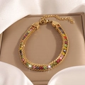 Close-up of gold chain bracelet with colorful zircons and lobster clasp on white silk - Multicolor